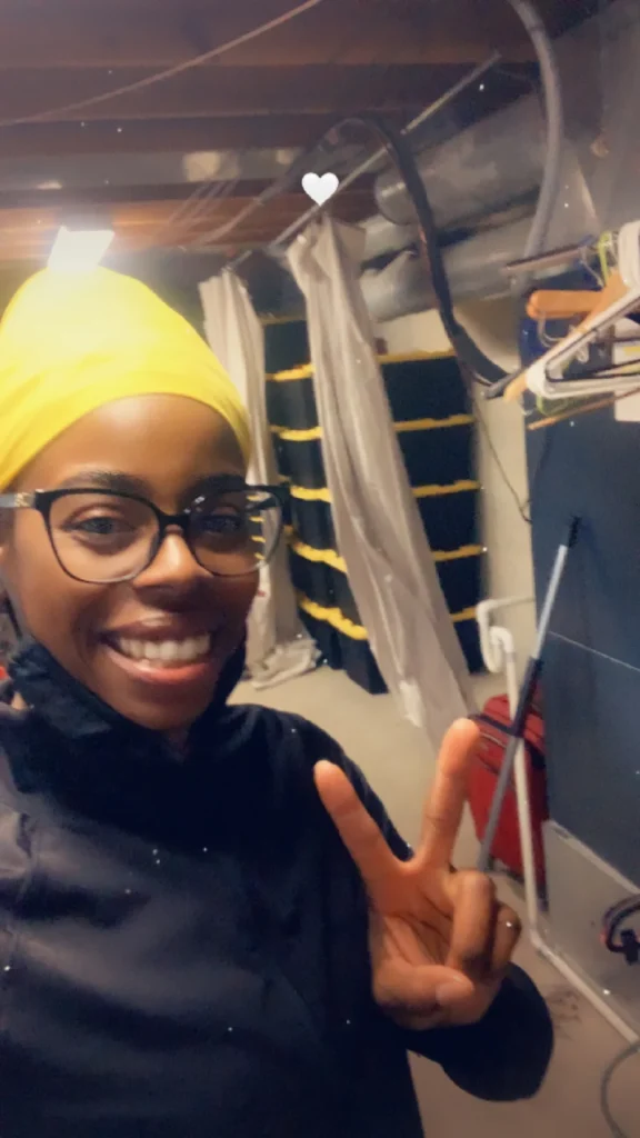Hadiyah smiling on the job in a yellow beanie