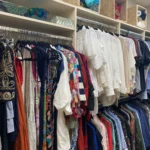 Walk-in closet with clothes hung above open shelves
