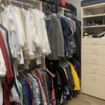 Walk-in closet with hanging clothes and a built-in dresser
