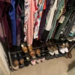 Closet with clothes hung above a shoe rack