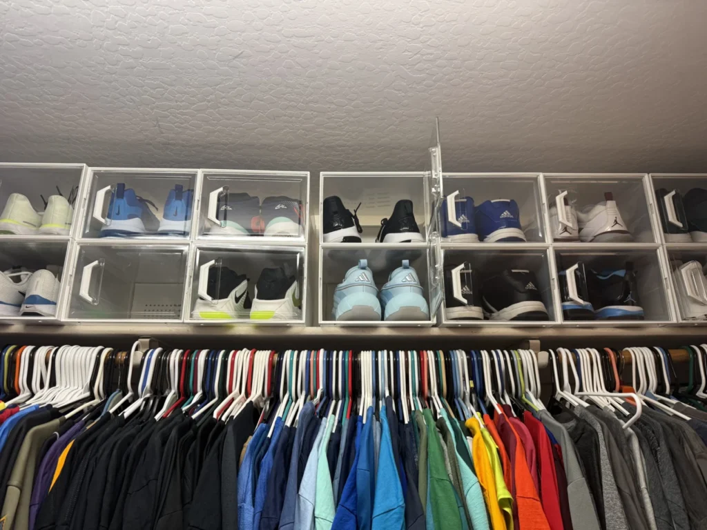 Shoe cubbies above a row of hanging shirts sorted by color