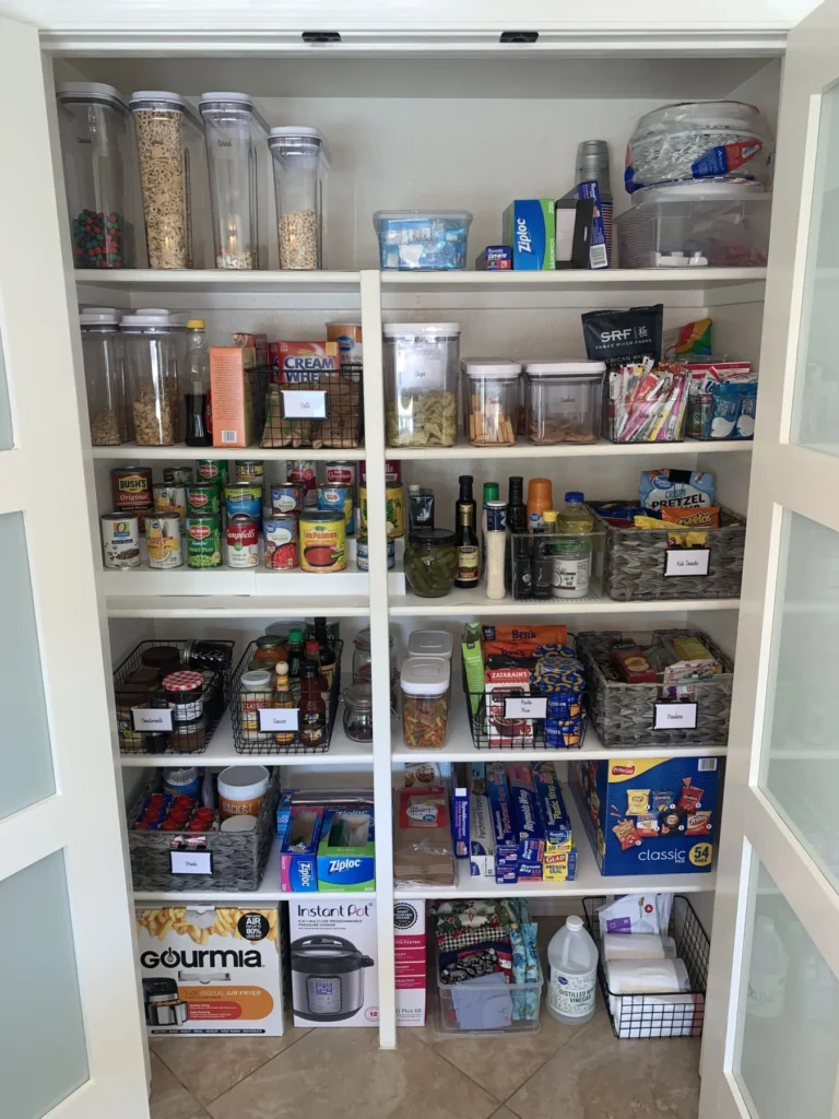Organized pantry with clear canisters and labeled bins on white shelves