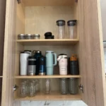 Cabinet with water bottles and tumblers lined up on shelves