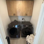 Laundry room with a front-load washer and dryer under wood cabinets