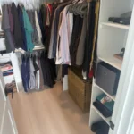 Walk-in closet with hanging clothes and shelves