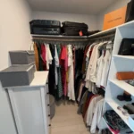 Walk-in closet with luggage stored on the top shelf