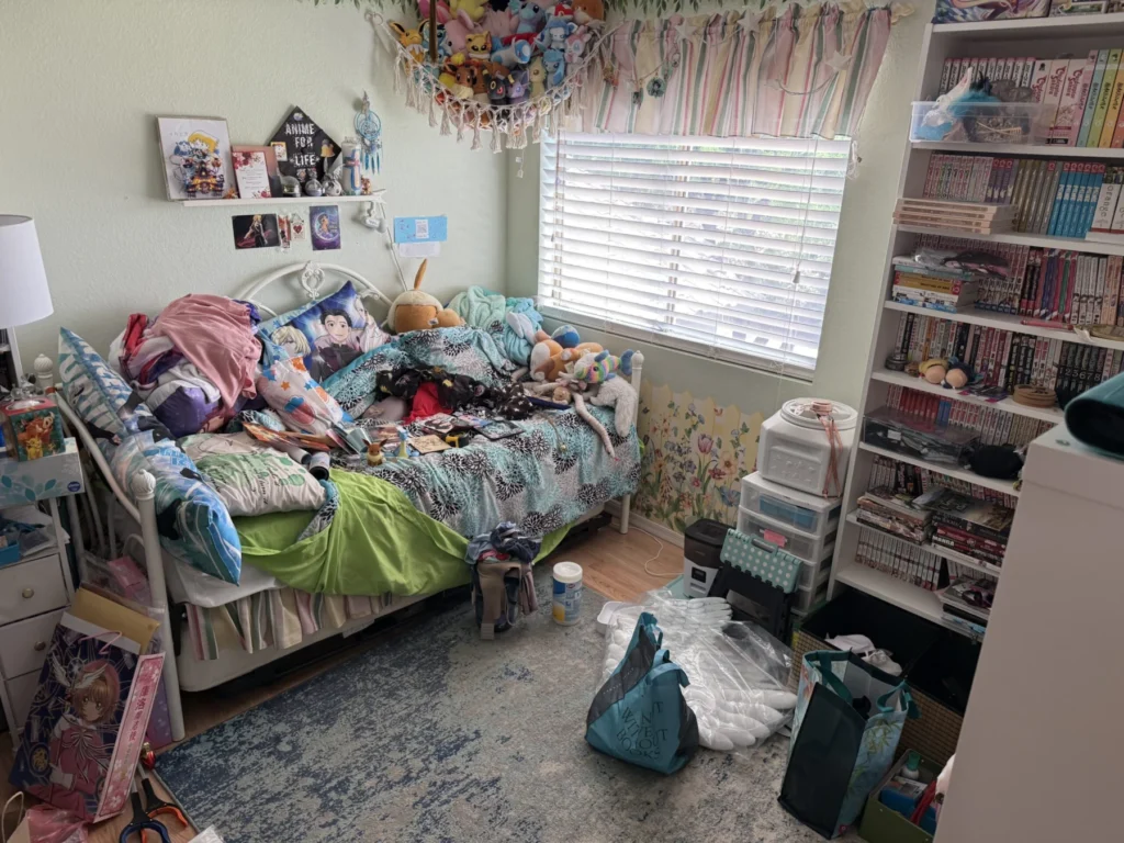 Child’s bedroom before organizing, with clothes and toys on the bed and floor