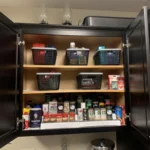 Kitchen cabinet after organizing, with spices and supplies in bins
