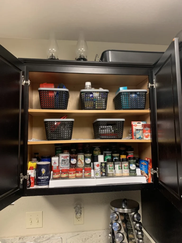 Kitchen cabinet after organizing, with spices and supplies in bins