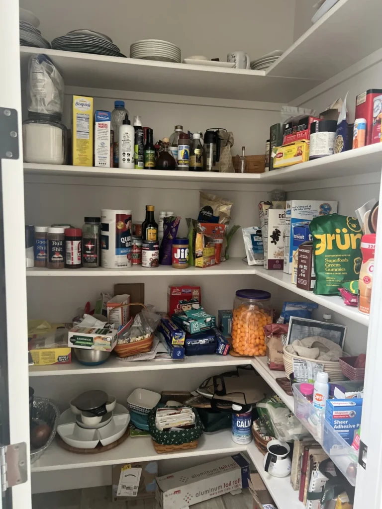 Pantry shelves before organizing, with mixed food and appliances