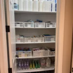 Linen and supply closet with labeled baskets on white shelves