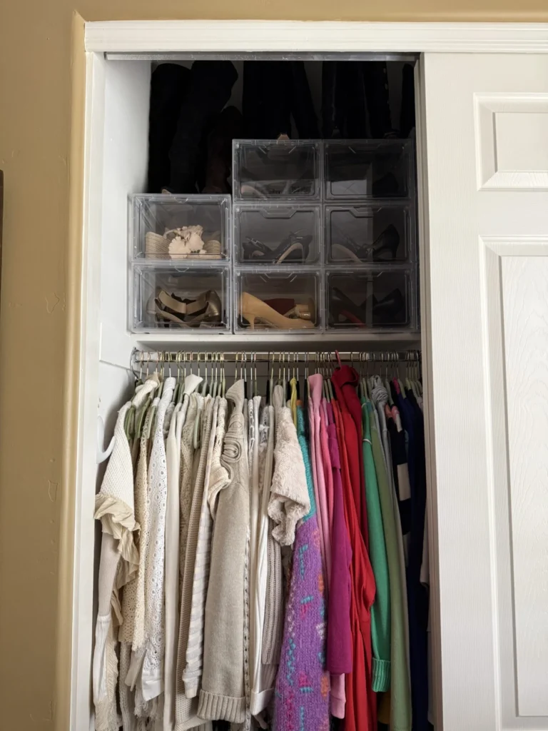 Reach-in closet after organizing, with clear drawers above hanging clothes