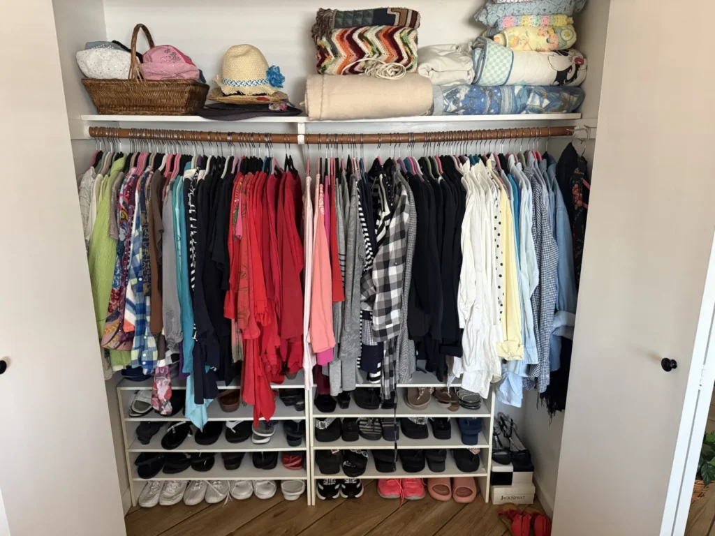Unpacked closet with shoes on a rack below hanging clothes
