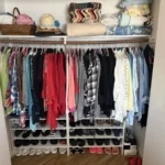 Unpacked closet with shoes on a rack below hanging clothes