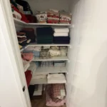 Reach-in closet with folded linens on wire shelves