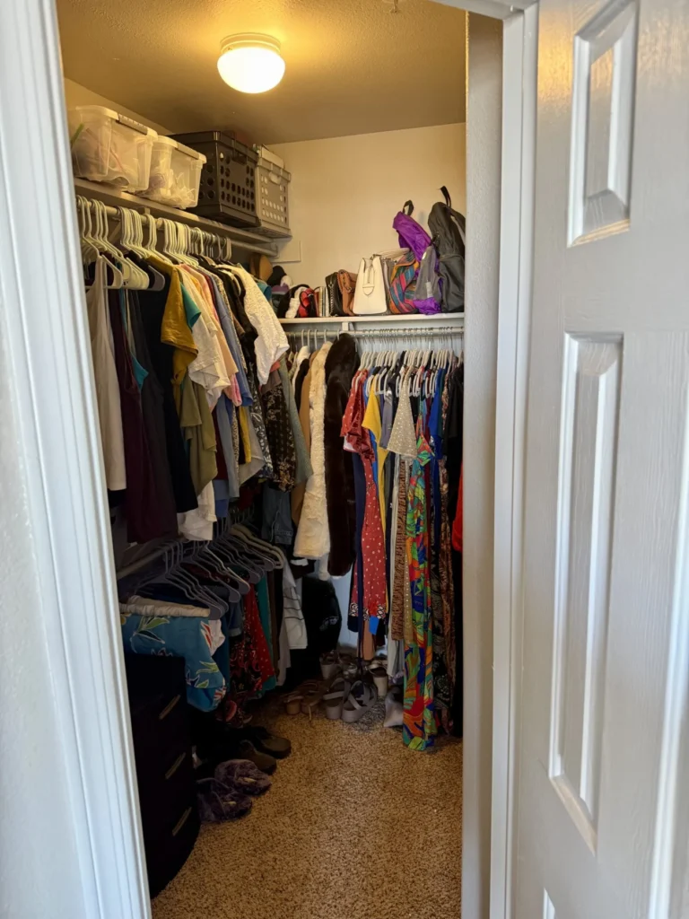 Walk-in closet before organizing, packed with clothes