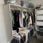 Walk-in closet with white shelving and hanging clothes