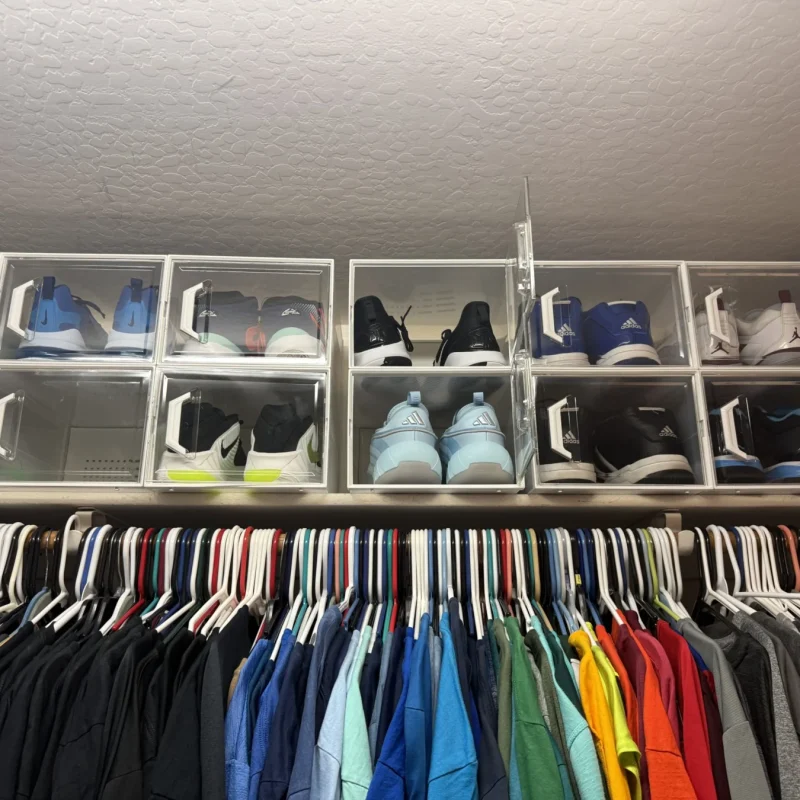 Shoe cubbies above a row of hanging shirts sorted by color