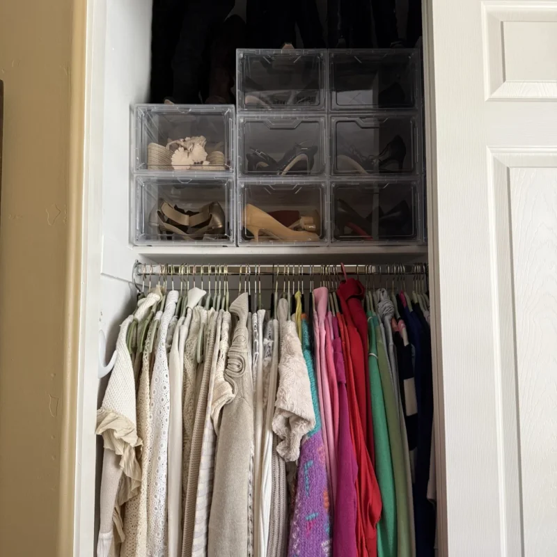 Reach-in closet after organizing, with clear drawers above hanging clothes