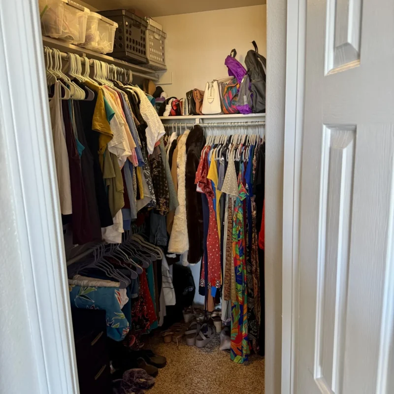 Walk-in closet before organizing, packed with clothes